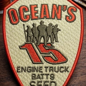 Può includere: Toppa ricamata con la scritta "OCEAN'S 16" in rosso e un gruppo di figure. La toppa include anche "ENGINE TRUCK BATT9 SFFD" in nero, il tutto su sfondo beige con bordo rosso.