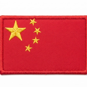 May include: A rectangular embroidered patch featuring a vibrant red background with one large yellow star and four smaller yellow stars arranged in an arc on the left side. The patch has a thick, stitched red border around the entire perimeter.