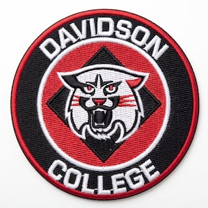 May include: A circular embroidered patch featuring a white wildcat head with red eyes and black accents centred on a black diamond. The background is red with a black border. The text DAVIDSON COLLEGE is stitched in white capital letters.