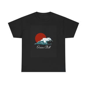 Może przedstawiać: Czarny t-shirt z grafiką czerwonego słońca zachodzącego nad stylizowaną falą oceanu. Fale są biało-turkusowe, z napisem "Ocean Chill" kursywą poniżej. Koszulka wykonana jest z miękkiego materiału.