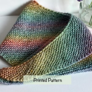 May include: A triangular knit scarf featuring a variegated colour gradient that transitions through shades of purple, blue, green, yellow, and orange. The fabric has a consistent garter stitch texture throughout, with the text Printed Pattern visible.