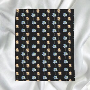May include: A black fabric with a repeating pattern of watercolor illustrations. The pattern features stacks of books with blue ribbons and wrapped gifts with gold bows. The overall design is a whimsical and artistic representation.