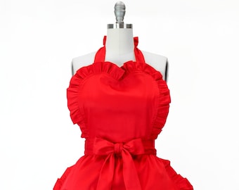 May include: A red heart-shaped apron with a ruffled trim and a bow tie. The apron has a single pocket on the front.