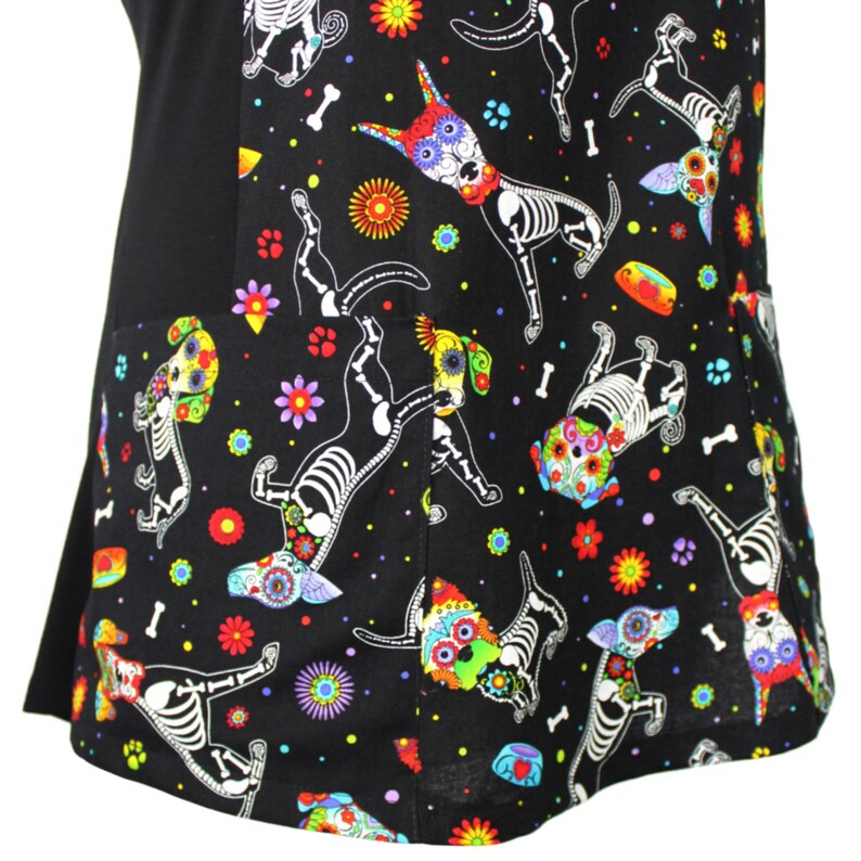 May include: Black scrub top with a colorful print of skeleton dogs with flowers and skulls. The print is on the bottom half of the top and the top half is solid black.