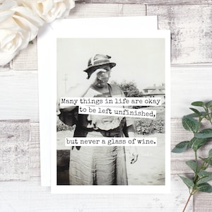 May include: Black and white photograph of a vintage greeting card. The card features a woman holding a glass of wine with text that reads, "Many things in life are okay to be left unfinished, but never a glass of wine."