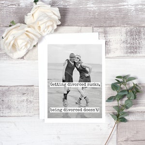 May include: Black and white photo of two women in vintage swimsuits standing on a beach. The text "Getting divorced sucks, being divorced doesn't!" is printed below the photo.
