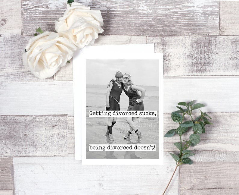 May include: Black and white photo of two women in vintage swimsuits standing on a beach. The text "Getting divorced sucks, being divorced doesn't!" is printed below the photo.