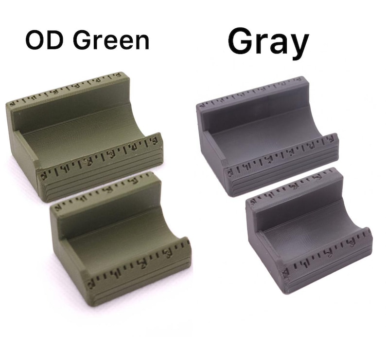 May include: Two small, curved, rectangular holders, one in OD green and the other in gray. Each has a ruler-like marking along the top and bottom edges. The text "OD Green" and "Gray" are above the respective holders.