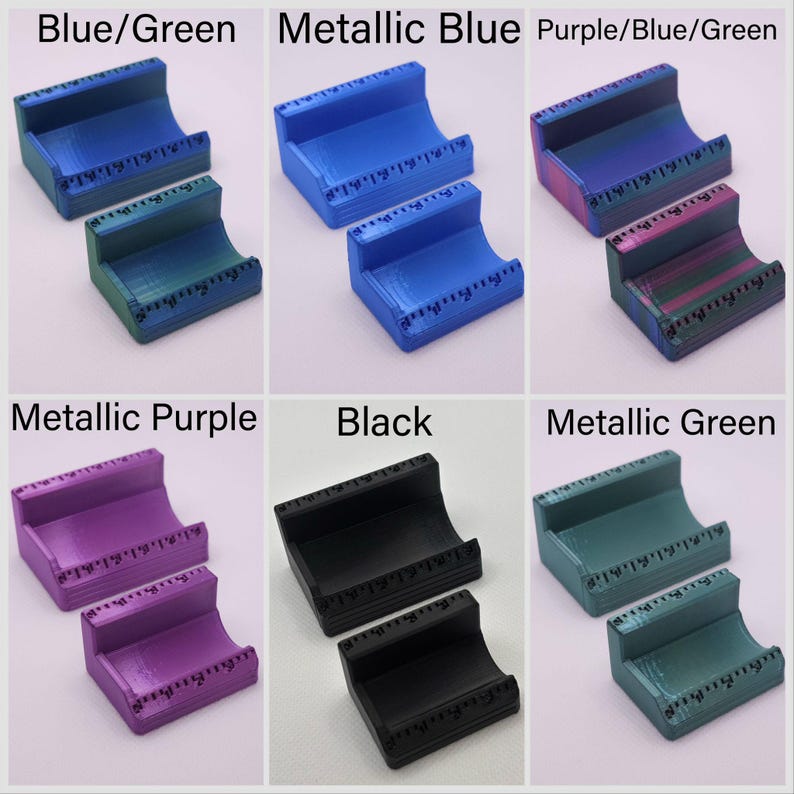 May include: A collection of 3D-printed card holders in various colors, including blue/green, metallic blue, purple/blue/green, metallic purple, black, and metallic green. Each holder has a curved design and a ruler-like detail along the top edge.