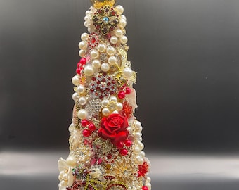 Puede incluir: Un árbol de Navidad decorativo adornado con perlas, rosas rojas y varias joyas. El árbol está adornado con una bicicleta dorada y una corona dorada en la parte superior. Está montado sobre una base dorada.