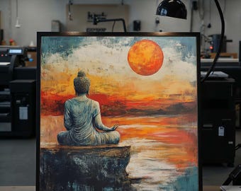 May include: Framed artwork depicting a serene Buddha statue in meditation, overlooking a sunset scene. The painting features a vibrant orange sun, with a color palette of blues, oranges, and yellows. The artwork is encased in a black frame.