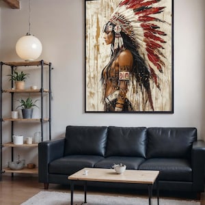 Può includere: Un'opera d'arte incorniciata raffigura una figura nativa americana di profilo, adornata da un copricapo di piume rosse, bianche e nere. L'opera è appesa sopra un divano in pelle nera, con un tavolino di legno e una mensola in metallo con piante.