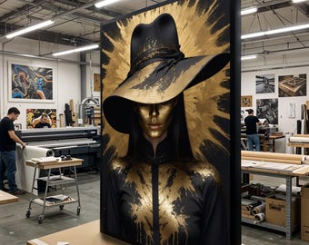 May include: A framed art print featuring a woman with gold skin and a black hat. The artwork has a gold and black color scheme, with gold paint splatter effects. The woman is wearing a black outfit.