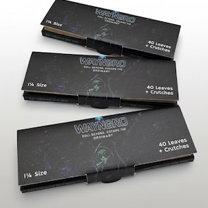 May include: Three black Wayngro rolling paper packs. Each pack has the text "WAYNGRO ROLL BEYOND, ESCAPE THE ORDINARY" and "40 Leaves + Crutches". The packs are 1 1/4 size and for tobacco use only.