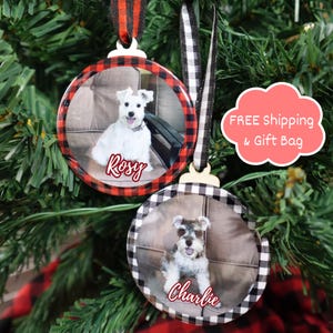 K&ouml;nnte beinhalten: Zwei runde Weihnachtsschmuckst&uuml;cke mit Hundefotos. Eines hat einen rot-schwarz karierten Rand und den Namen "Rosy". Das andere hat einen schwarz-wei&szlig; karierten Rand und den Namen "Charlie". Beide haben Aufh&auml;ngeb&auml;nder.