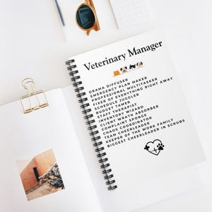 May include: A spiral-bound notebook with the title "Veterinary Manager" in black text. The notebook's white pages list various job roles, including "Drama Diffuser" and "Emergency Plan Maker." A gold paper clip and sunglasses are also visible.