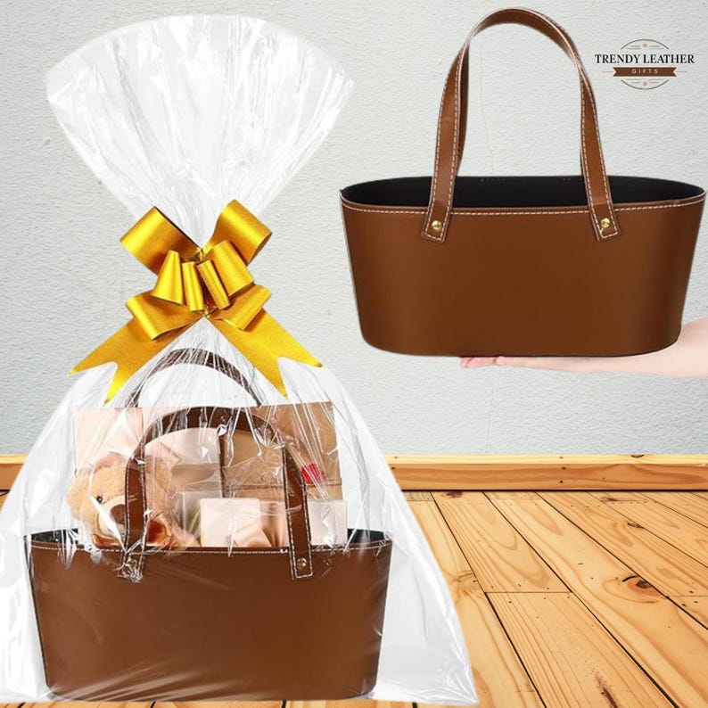 May include: A brown leather gift basket with a matching handle, presented in cellophane and tied with a gold bow. The basket is filled with gifts, and another basket is shown separately. The Trendy Leather logo is visible.