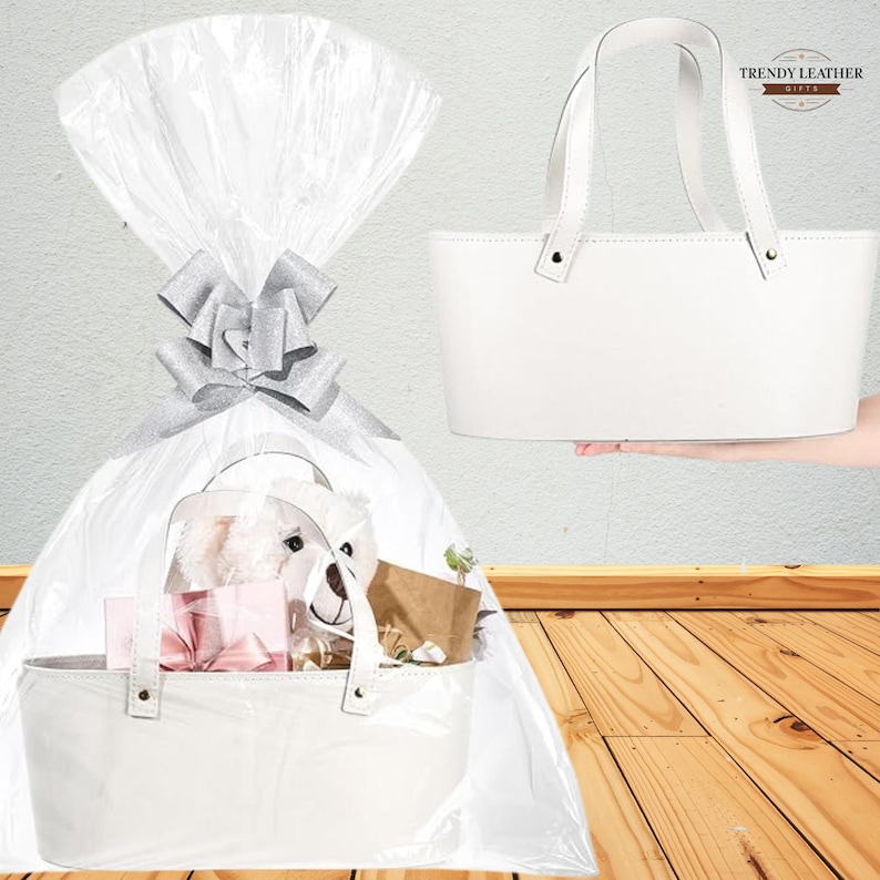 May include: A white leather gift basket with a handle, filled with gifts and wrapped in clear cellophane with a silver bow. A second basket is held up, showing the handle and the Trendy Leather Gifts logo.