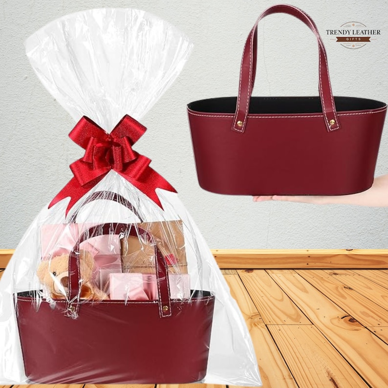 May include: A burgundy leather gift basket with white stitching and handles, filled with gifts and wrapped in clear cellophane. A red bow adorns the top. A second basket is shown separately.