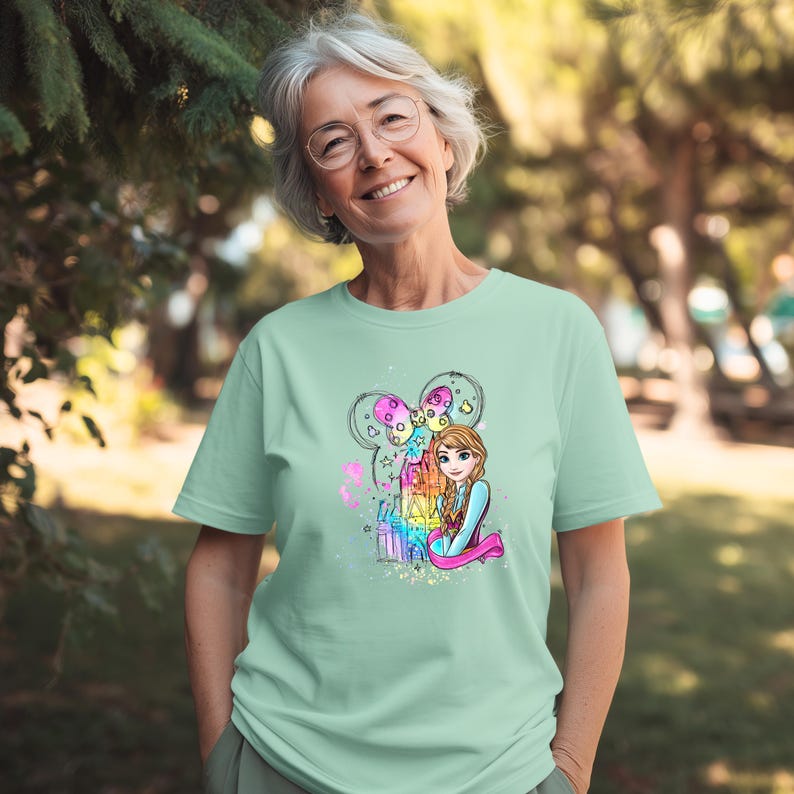 A smiling woman wearing a green t-shirt with a colorful graphic of a cartoon character.