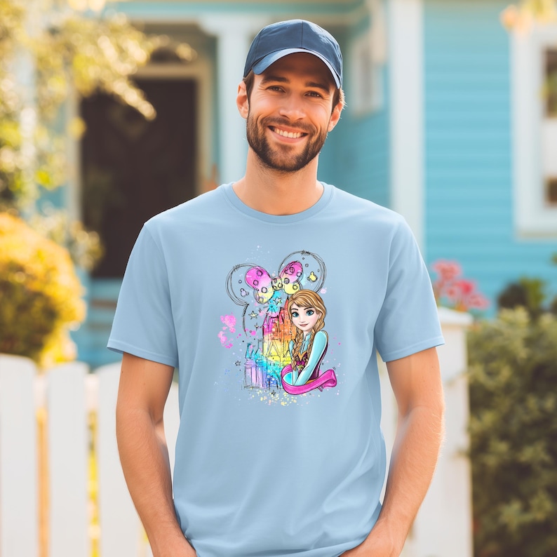 A smiling man wearing a blue t-shirt with a colorful graphic of a cartoon girl.