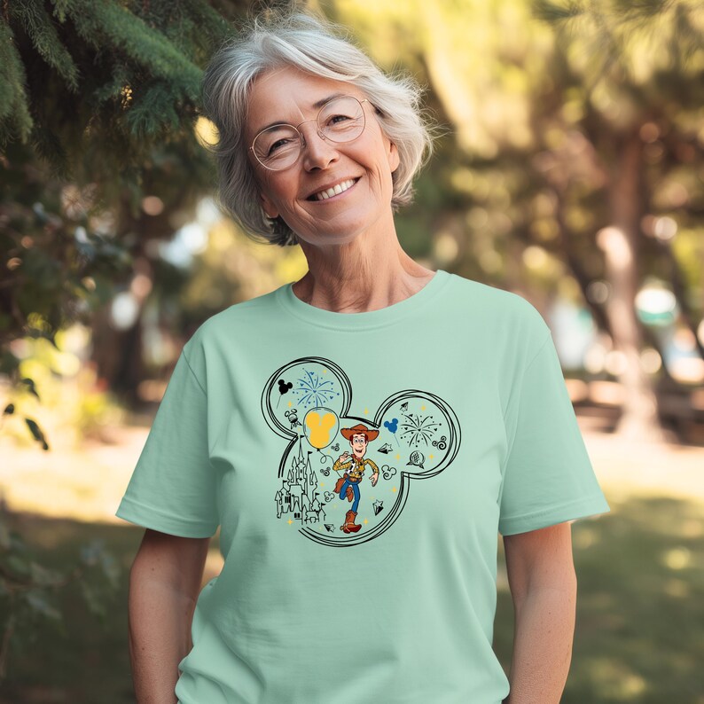 A smiling woman wearing a green t-shirt with a Mickey Mouse design.