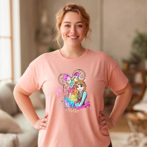 A smiling woman wearing a pink t-shirt with a colorful graphic of a cartoon character.
