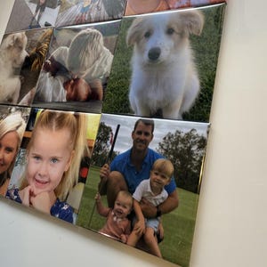 May include: A collection of square photo tiles arranged in a grid. The images feature various subjects, including children, a puppy, and a family. The photos are displayed on a white surface, creating a personalized wall art display.