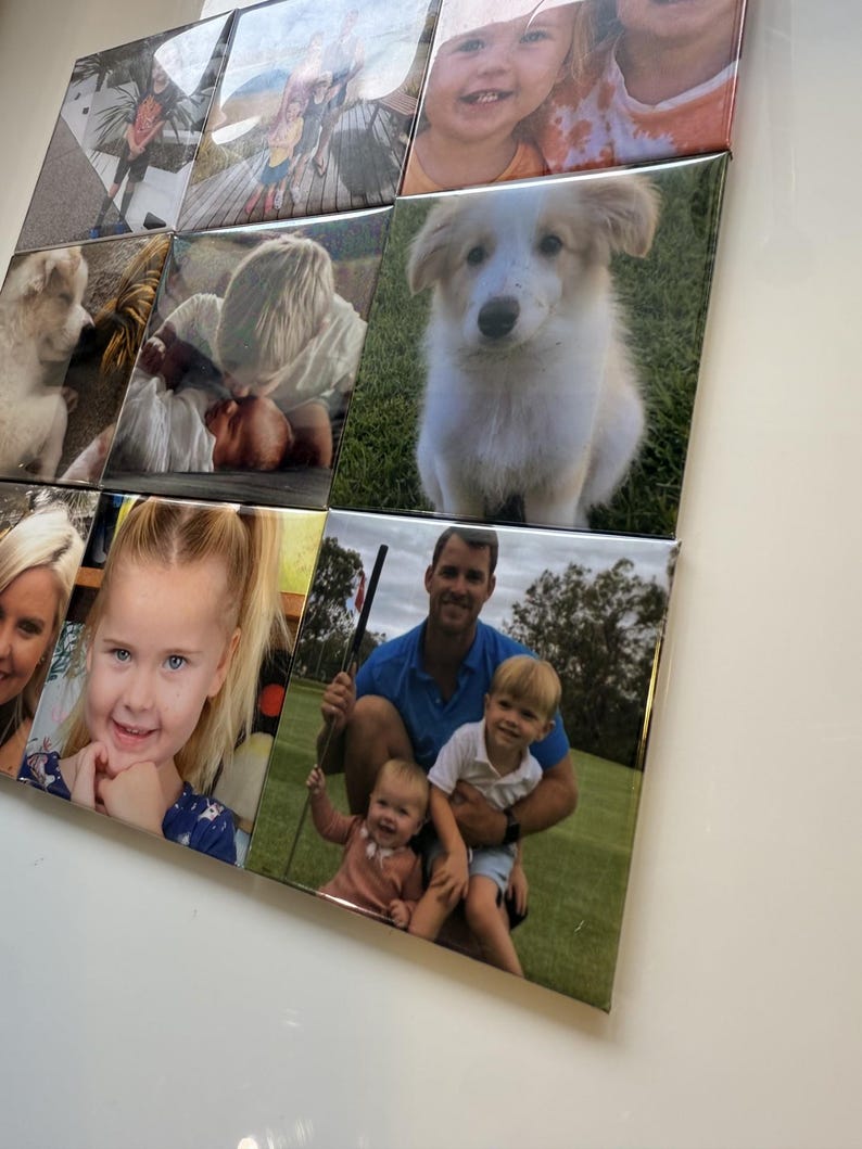 May include: A collection of square photo tiles arranged in a grid. The images feature various subjects, including children, a puppy, and a family. The photos are displayed on a white surface, creating a personalized wall art display.