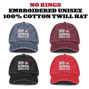 May include: Four embroidered unisex cotton twill hats in different colors: denim blue, burgundy, black, and red. Each hat features the text "NO KINGS SINCE 1776" in white. The hats are vintage-washed for a worn look.