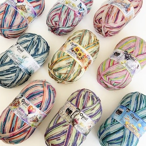 May include: Nine skeins of Opal Aquarell yarn in various color combinations. Each skein is wrapped with a label displaying the brand name and product details. The yarn colors include shades of blue, green, pink, purple, and yellow.