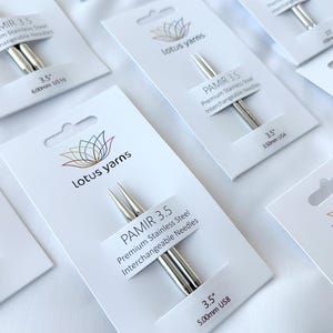 May include: Close-up of several packages of PAMIR 3.5 premium stainless steel interchangeable knitting needles. Each package displays the Lotus Yarns logo and needle size, with measurements in mm. The needles are silver and have sharp tips.