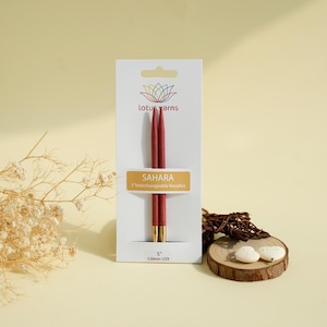 Puede incluir: Un par de agujas de tejer intercambiables Sahara de 5 pulgadas de Lotus Yarns, con mangos de madera de color rojo oscuro y puntas metálicas, montadas en una tarjeta blanca con el nombre de la marca y la medida 5,50 mm US9.