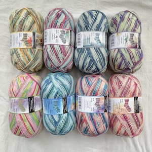 May include: Eight skeins of Aquarrell yarn in various colors, including pink, blue, green, and purple. Each skein has a label with the word "AQUARELL" and the number "3716". The yarn is arranged on a white surface.