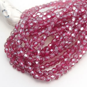 May include: A strand of faceted glass beads in a deep pink colour with a silver shimmer.