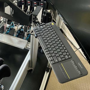 Può includere: Configurazione di simulatore di corse nera con volante, sedile e pedali. Una tastiera nera con touchpad è montata lateralmente. Il sedile ha la scritta "sparco".