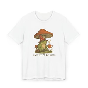 Hoppy To Be Here T-Shirt, Funny Frog Tee, Graphic Tee, Cottagecore Mushroom Shirt, Gift for Frog Lovers, Humor Tee