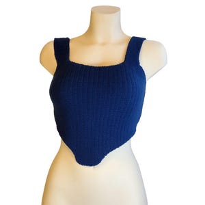 May include: A navy blue knitted crop top with a square neckline and wide straps. The top has a triangular hemline and is displayed on a mannequin. The fabric appears to be a medium-weight knit.