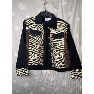 May include: A long-sleeve jacket featuring a black collar, sleeves, and hem. The front panels display a mix of vertical stripes with zebra print, leopard print, and a brown textured pattern. It includes a button-down front and two chest pockets.
