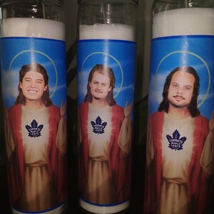 May include: Three glass candle jars with blue and white labels featuring images of men with long hair and beards. The labels also include the text "Toronto Maple Leafs".