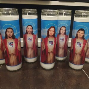 May include: Seven glass candle holders featuring images of hockey players dressed as Jesus. Each candle holder has a blue background with a white and red New York Rangers logo.