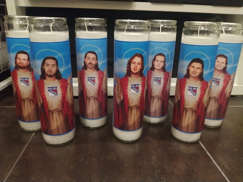May include: Seven glass candle holders featuring images of hockey players dressed as Jesus. Each candle holder has a blue background with a white and red New York Rangers logo.