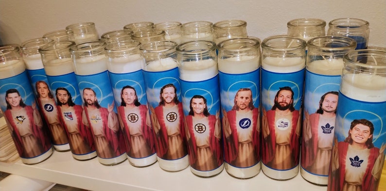 May include: A row of 15 white candles with images of hockey players dressed as Jesus. Each candle features a different player and a different hockey team logo.