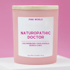May include: A pink soy wax candle with a wooden lid. The label reads "PINK WORLD NATUROPATHIC DOCTOR I FIX PROBLEMS YOUR GOOGLE SEARCH CAN'T." The candle is 9 oz.