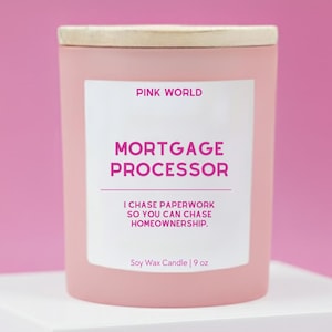 May include: A pink soy wax candle with a wooden lid. The label reads "PINK WORLD" and "MORTGAGE PROCESSOR". The text below says "I CHASE PAPERWORK SO YOU CAN CHASE HOMEOWNERSHIP." The candle is 9 oz.
