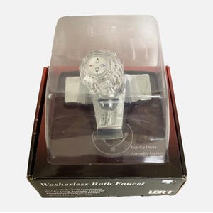May include: A washerless bath faucet with a clear, faceted knob handle featuring ON, OFF, and directional arrows. The faucet is housed in clear plastic packaging atop a black box labeled Washerless Bath Faucet and Pop-Up Drain Assembly Included.