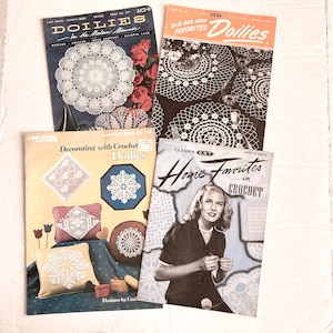 May include: Four vintage crochet pattern booklets. Titles include "Doilies in the Modern Manner," "Old and New Favorites Doilies," "Decorating with Crochet Doilies," and "Home Favorites in Crochet." The covers feature doily designs and illustrations.