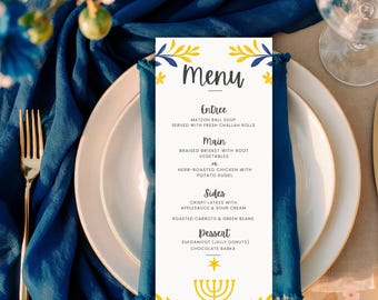 May include: A menu card with a white background, gold trim, and a blue napkin. The menu lists Entree, Main, Sides, and Dessert options. The card is decorated with yellow and blue floral accents and the words "Happy Hanukkah".