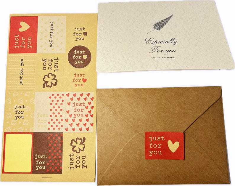 May include: A collection of stationery items, including stickers, cards, and an envelope. The stickers feature the text "just for you" with heart and clover designs. One card has the text "Especially For you" and a feather illustration. The envelope has a red sticker with a heart.