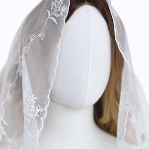 Puede incluir: Una taza de cerámica blanca con un asa negra y el texto "But First, Coffee" en negrita negra. La taza se encuentra sobre un fondo borroso, sugiriendo un ambiente acogedor.